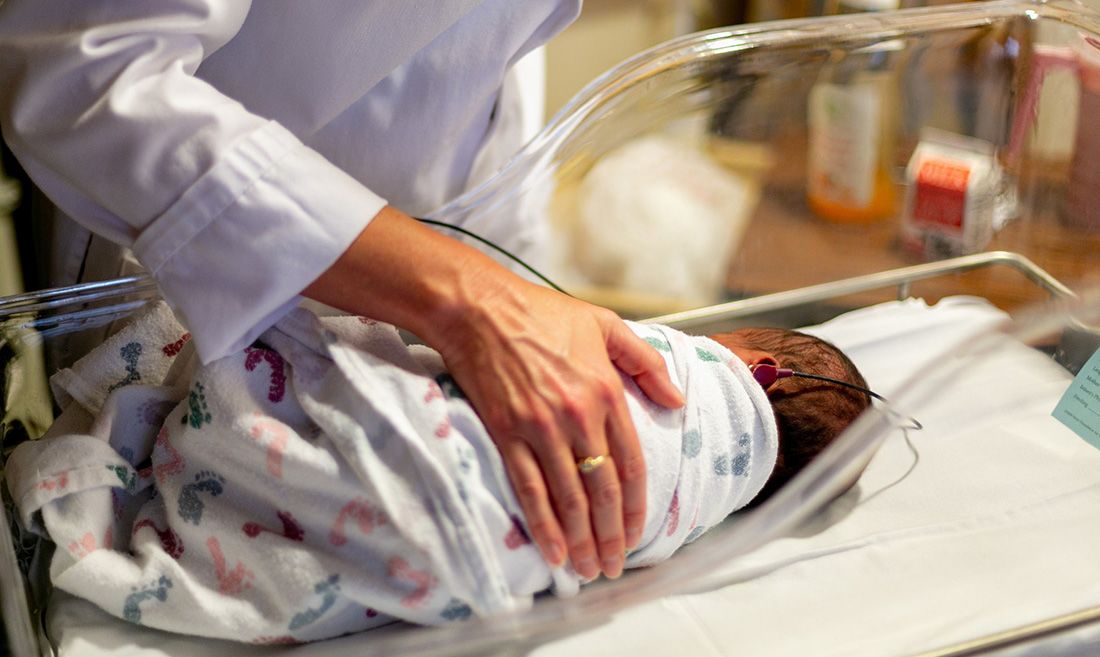 health worker's hand with infant in medical setting