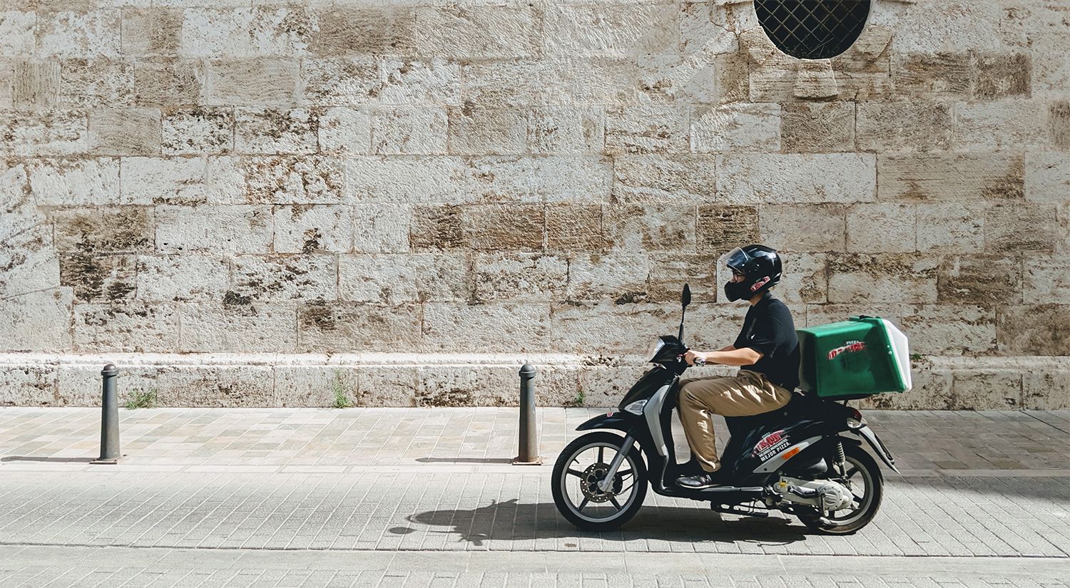 Delivery driver on a scooter with food delivery box on the back