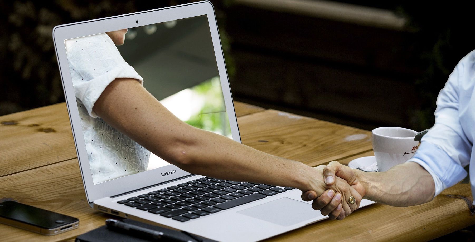 graphic of an arm reaching out of a laptop screen to shake someone's hand