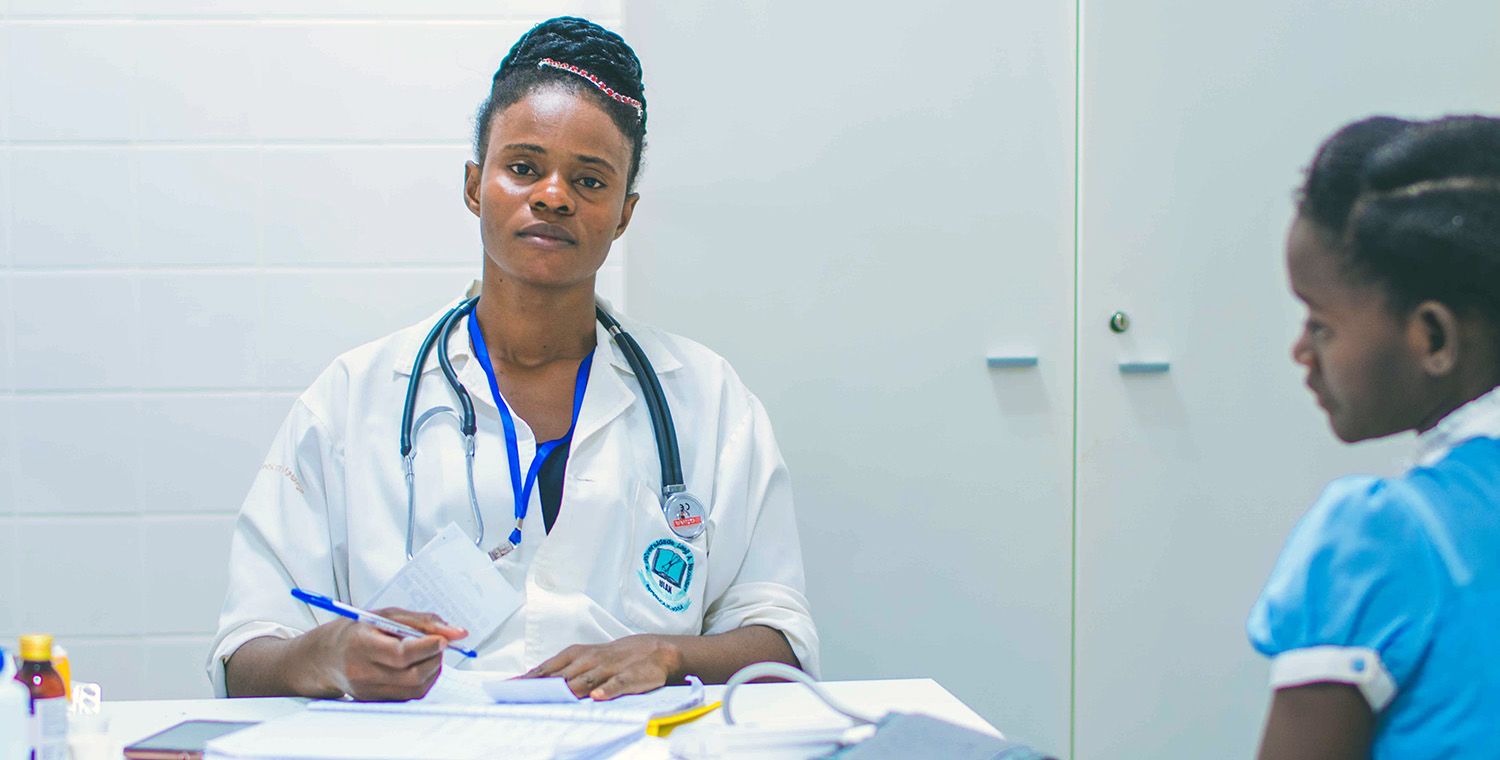 health worker looking at camera with child looking at the worker