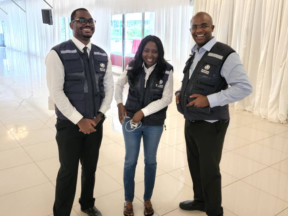 Mary stands between two men, other WHO colleagues, smiling for a photograph