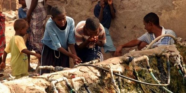 A group of children drinking from taps on the street.