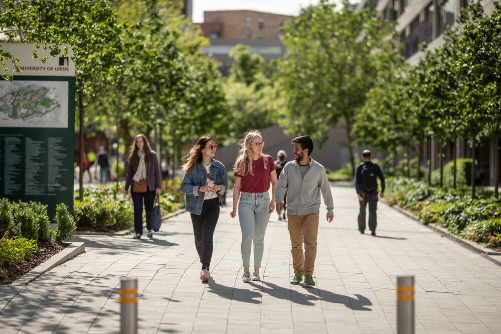 Three students walking together outside on campus on a sunny day