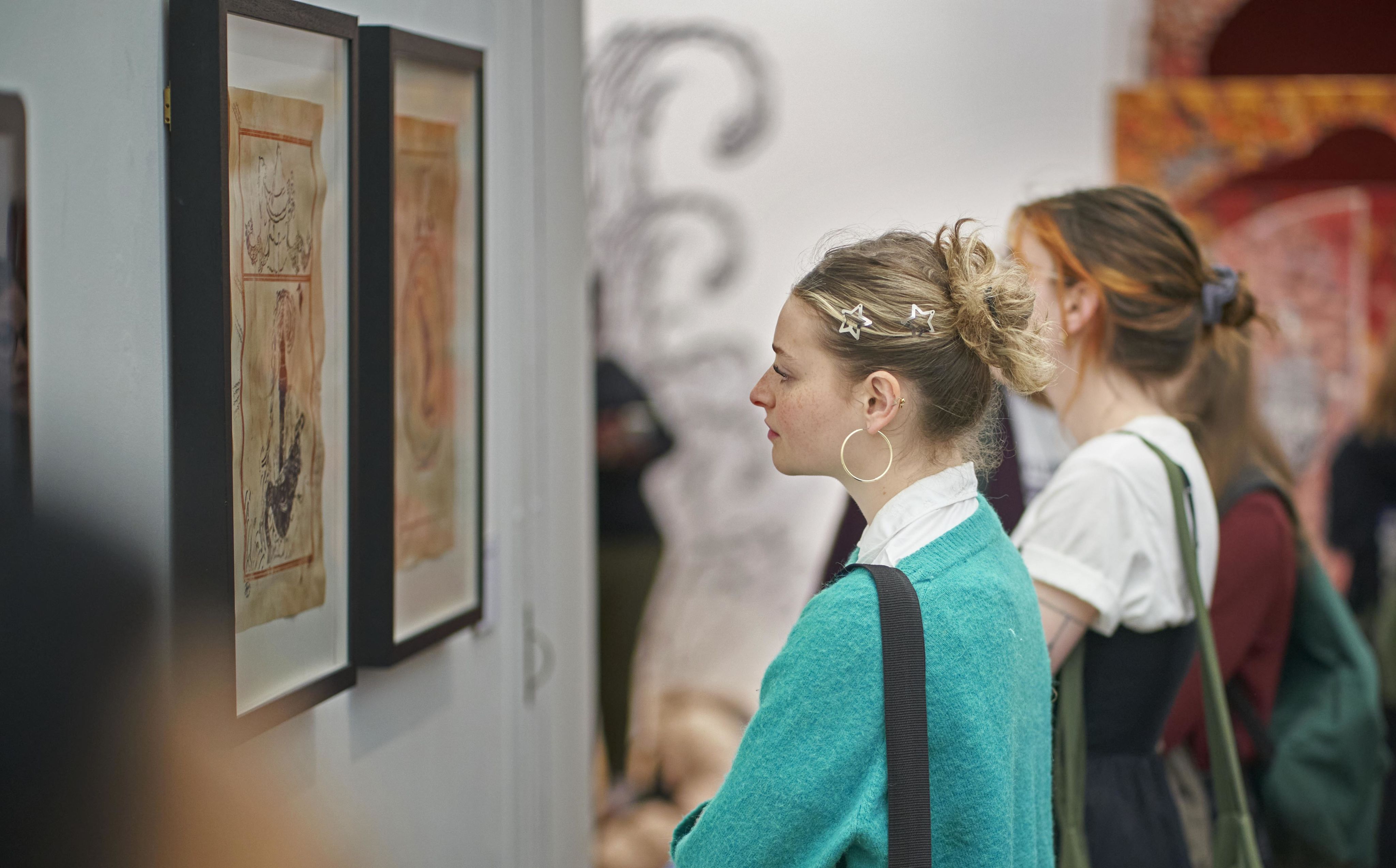 Two students looking at artwork in an exhibition.