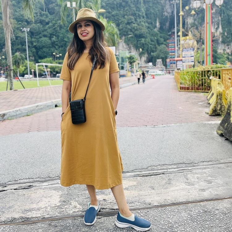 Photo of Sunayana Nandagopal wearing a yellow dress, yellow hat and blue shoes.