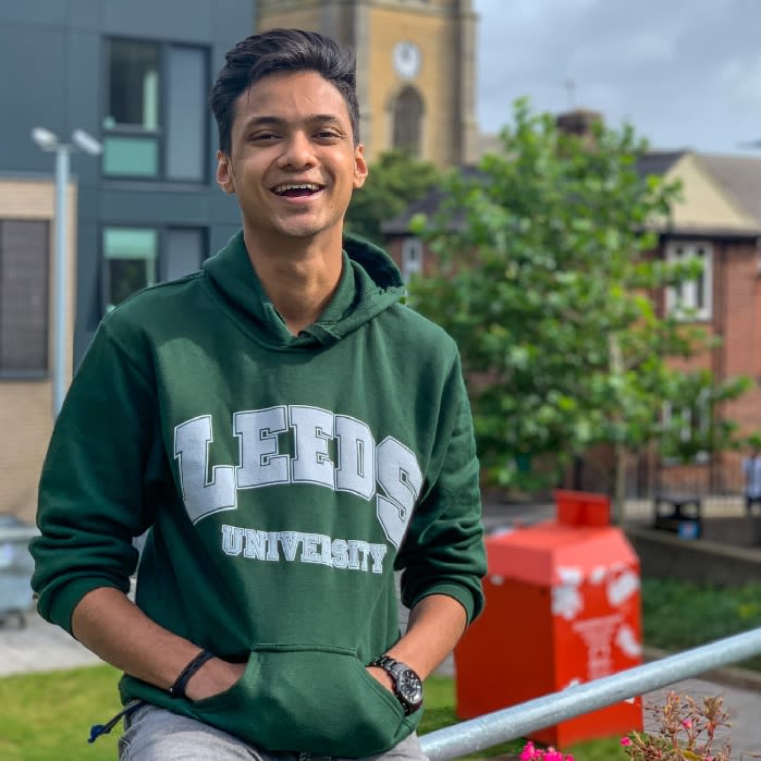 Tejas Shah smiling at the camera and wearing a green university of leeds hoodie