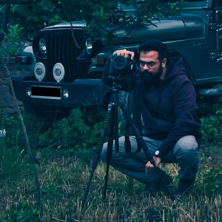 Image of Nitin Pasricha crouching behind a camera taking a photo.