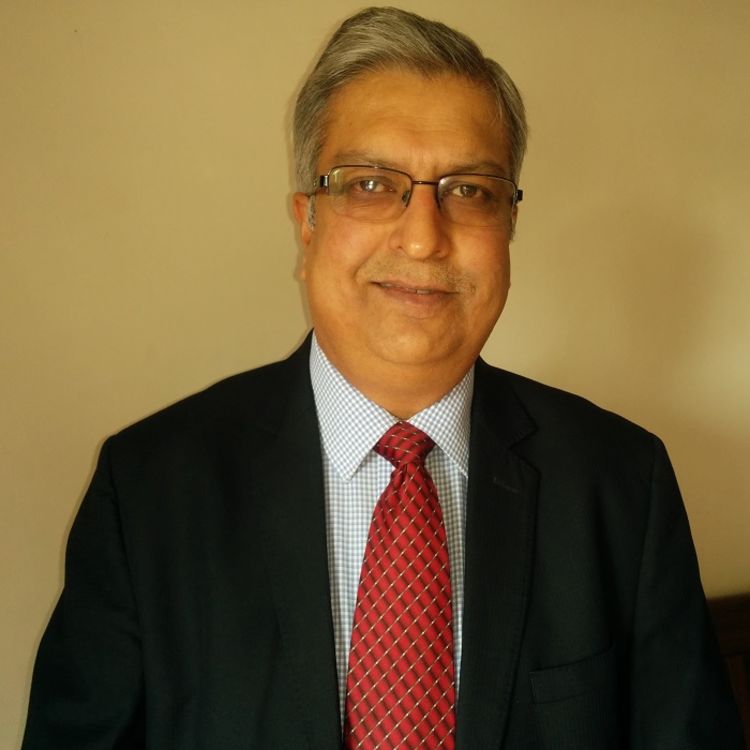 Photo of Shantanu Sen Sharma wearing a black suit, white shirt and red tie