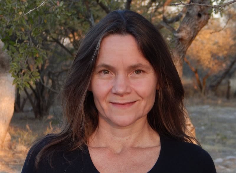 Rebecca Klein stands outside in Botswana in front of a tree, she is smiling for the camera