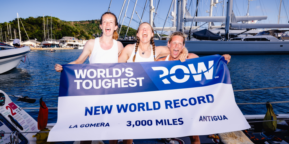 Three women hold a world record banner, celebrating