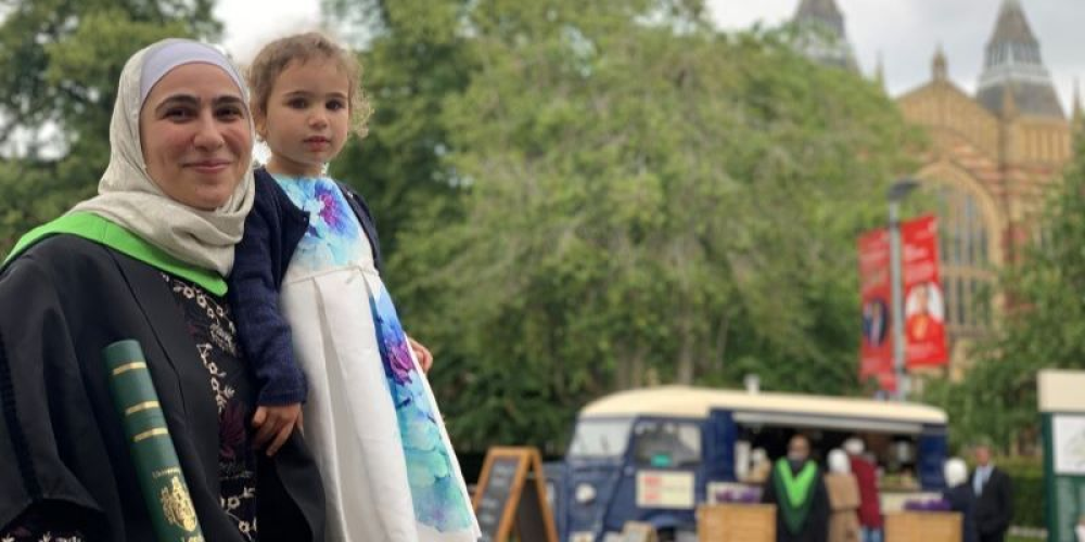 Loubna sits on campus on graduation day with her daughter