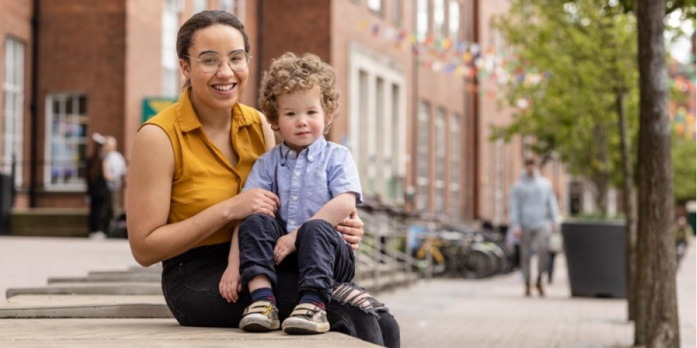 Natasha sits with her son Oscar on her knee outside the Student Union