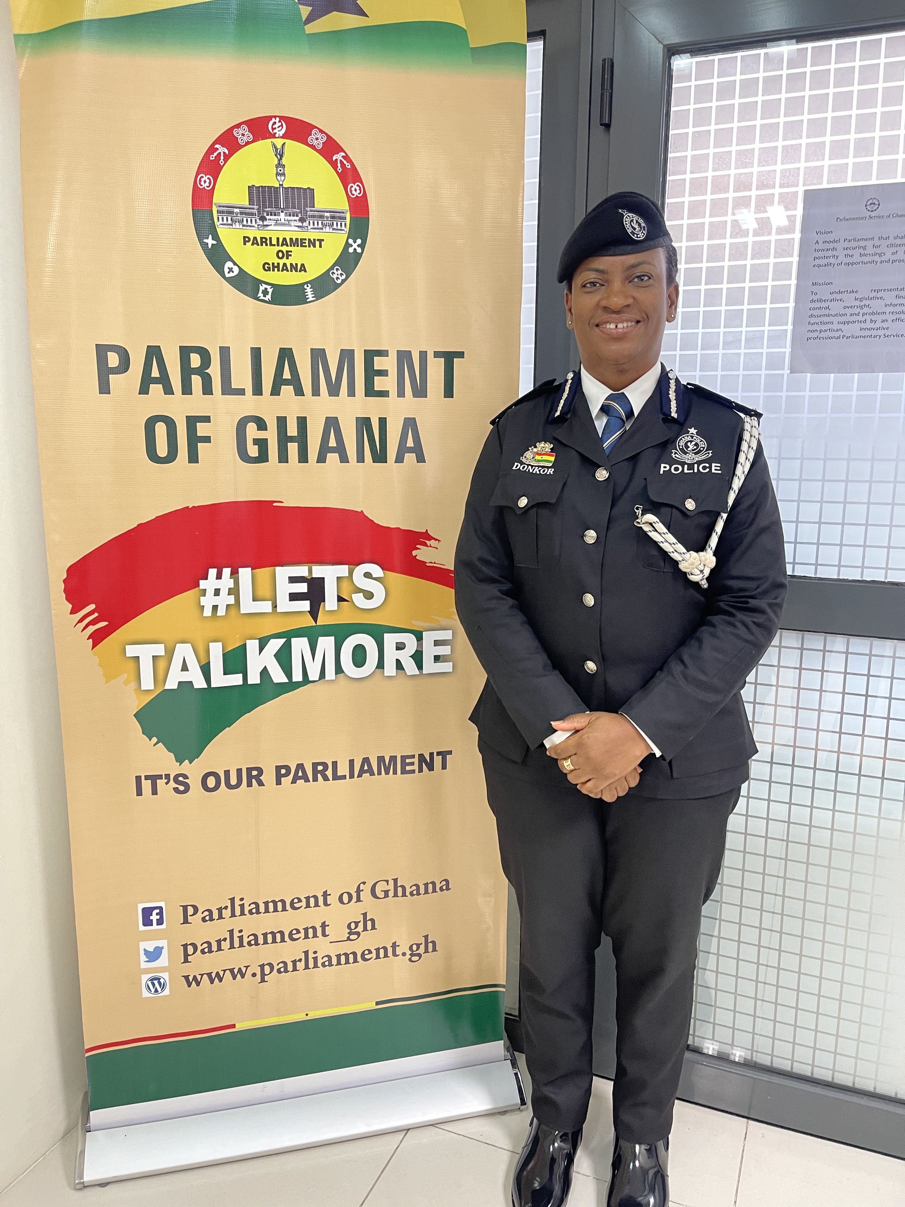 woman looking at camera wearing police uniform beside banner