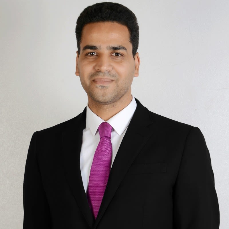 head and shoulder photo of man in jacket and tie looking at camera