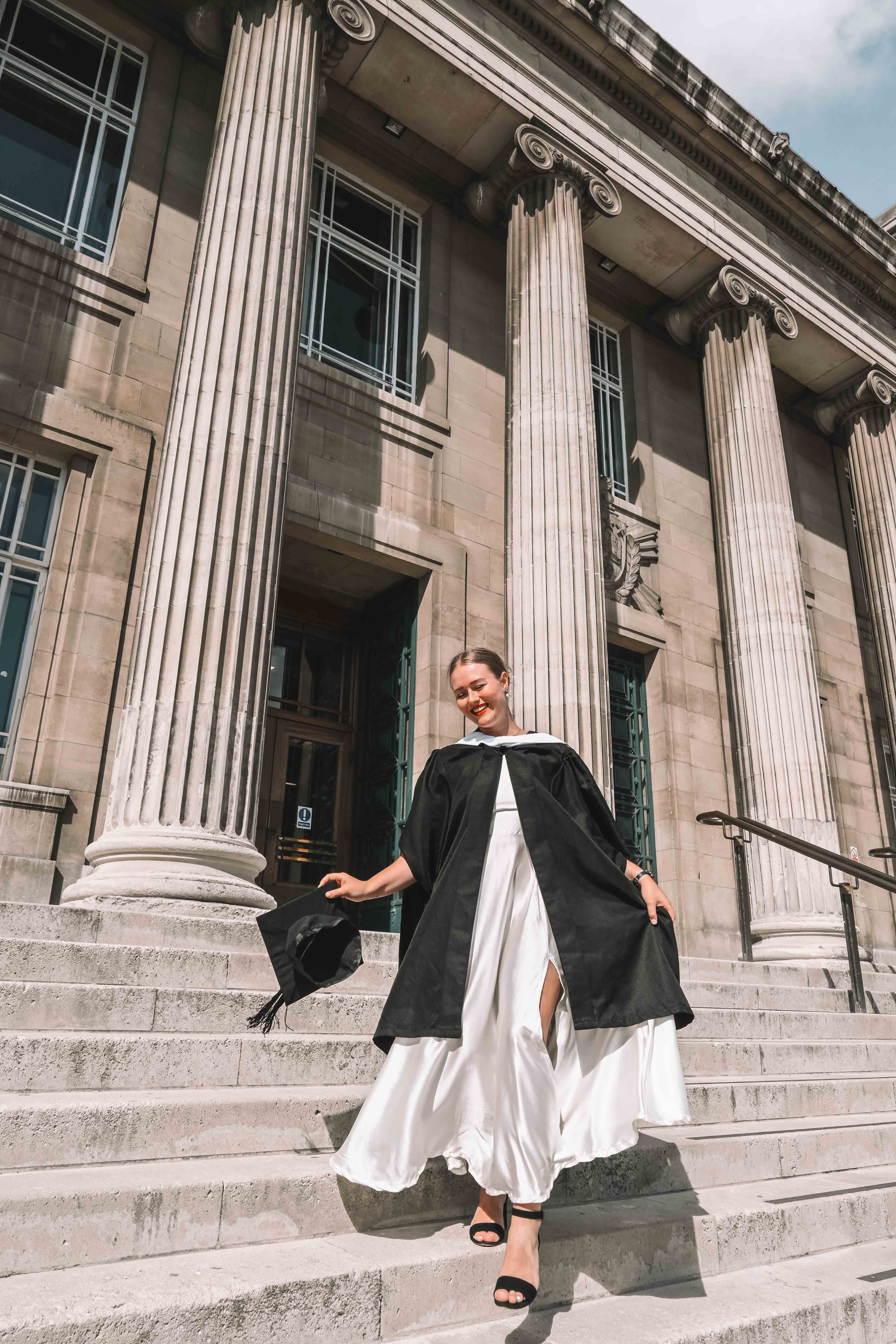 woman in graduation gown standing on the Parkinson Building steps