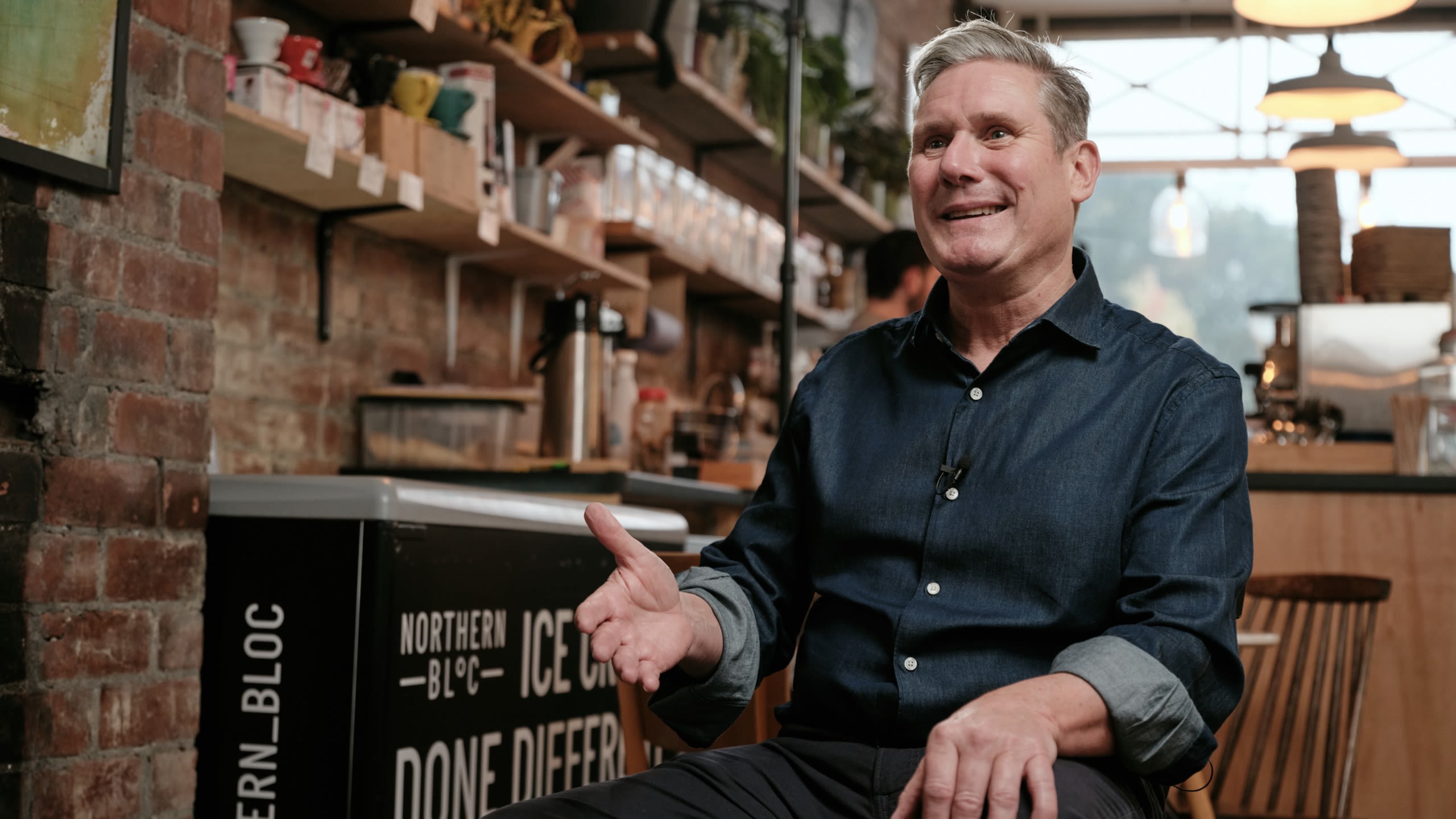 Keir Starmer sat in a bright, modern cafe bar, gesturing and talking