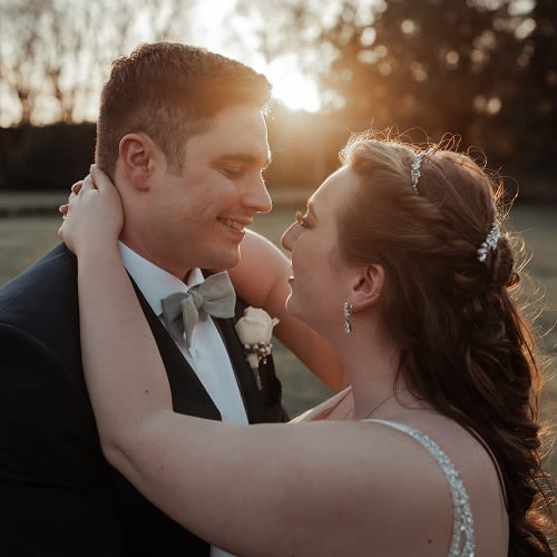 A couple on their wedding day embracing and looking at each other. Some lens flare is caused by the setting sun behind them