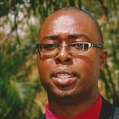 Portrait photo of a man wearing glasses, a red shirt and black suit jacket
