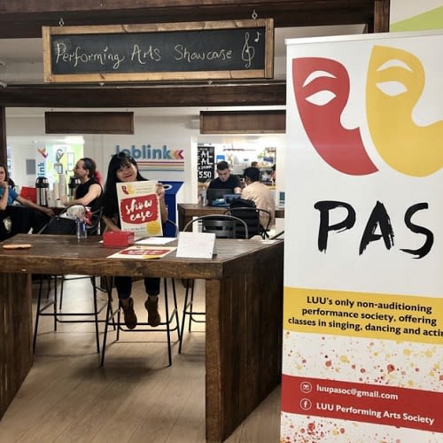Woman sat at a table in the student union advertising the Performing Arts Showcase
