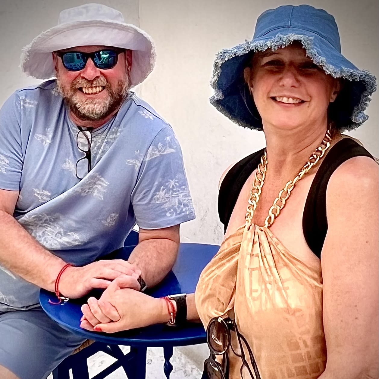 Man and woman holding hands and wearing hats, smiling for the camera