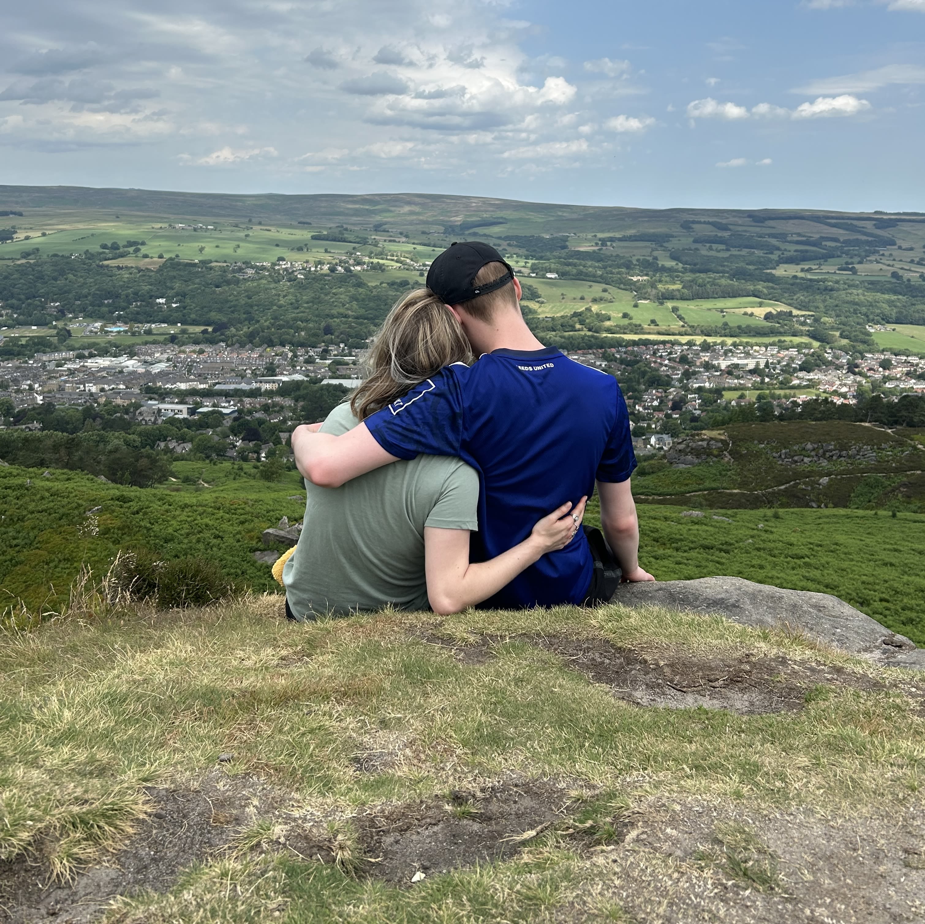 A man and a woman embracing on the cow and calf in Ilkley. The photo is taken from behind
