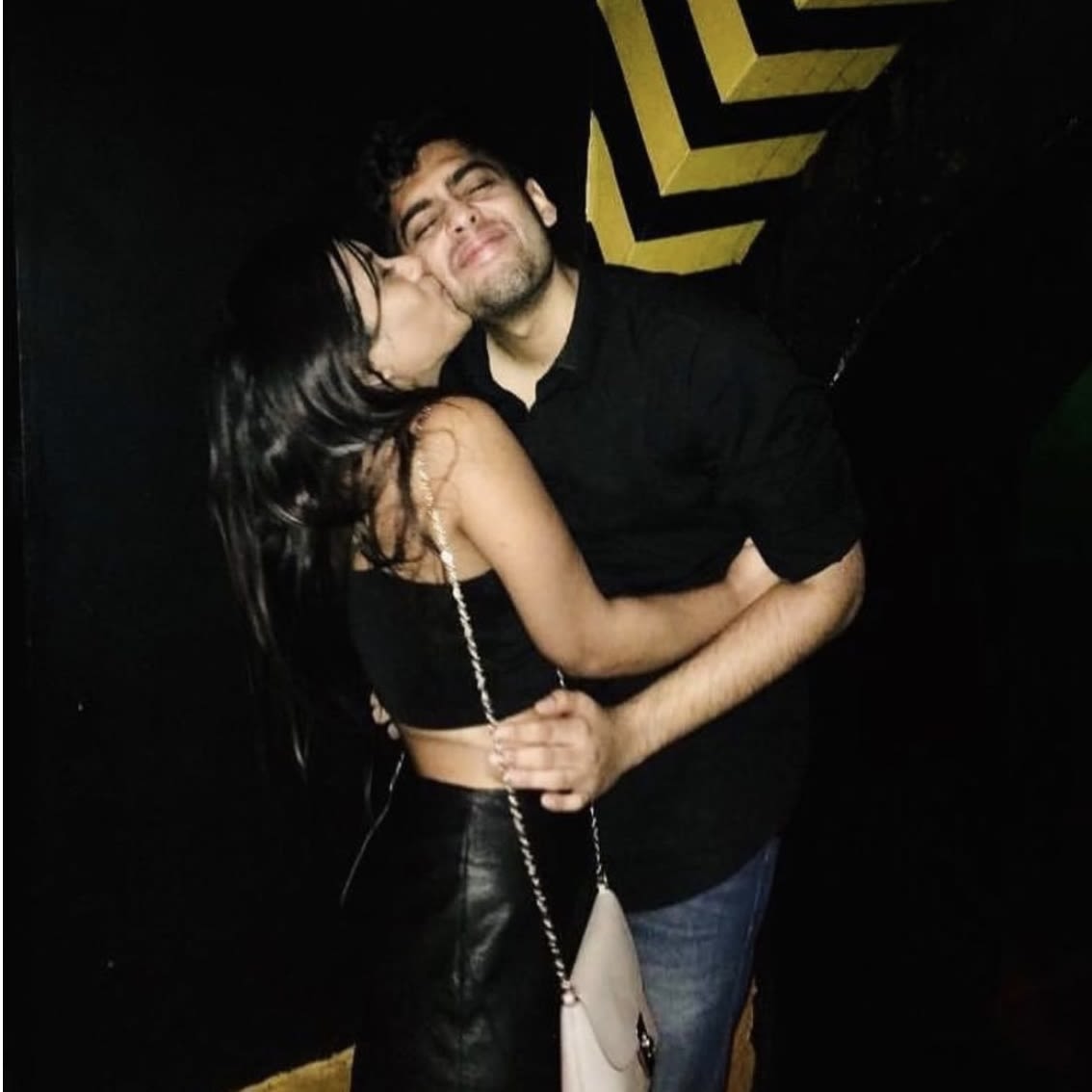 A photo of a man and woman embracing. She is kissing him on the cheek