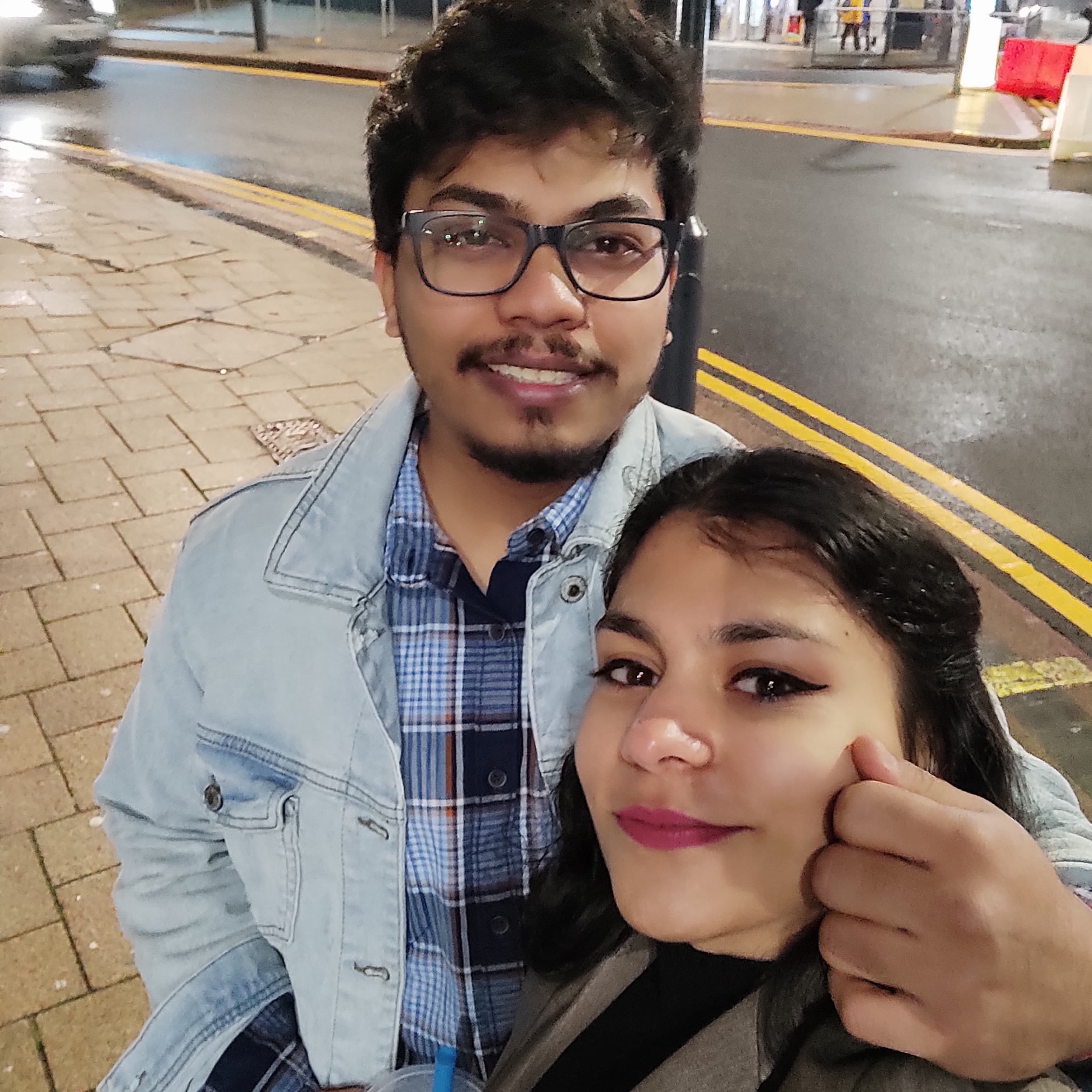A man and a woman embracing in the street and smiling for the camera
