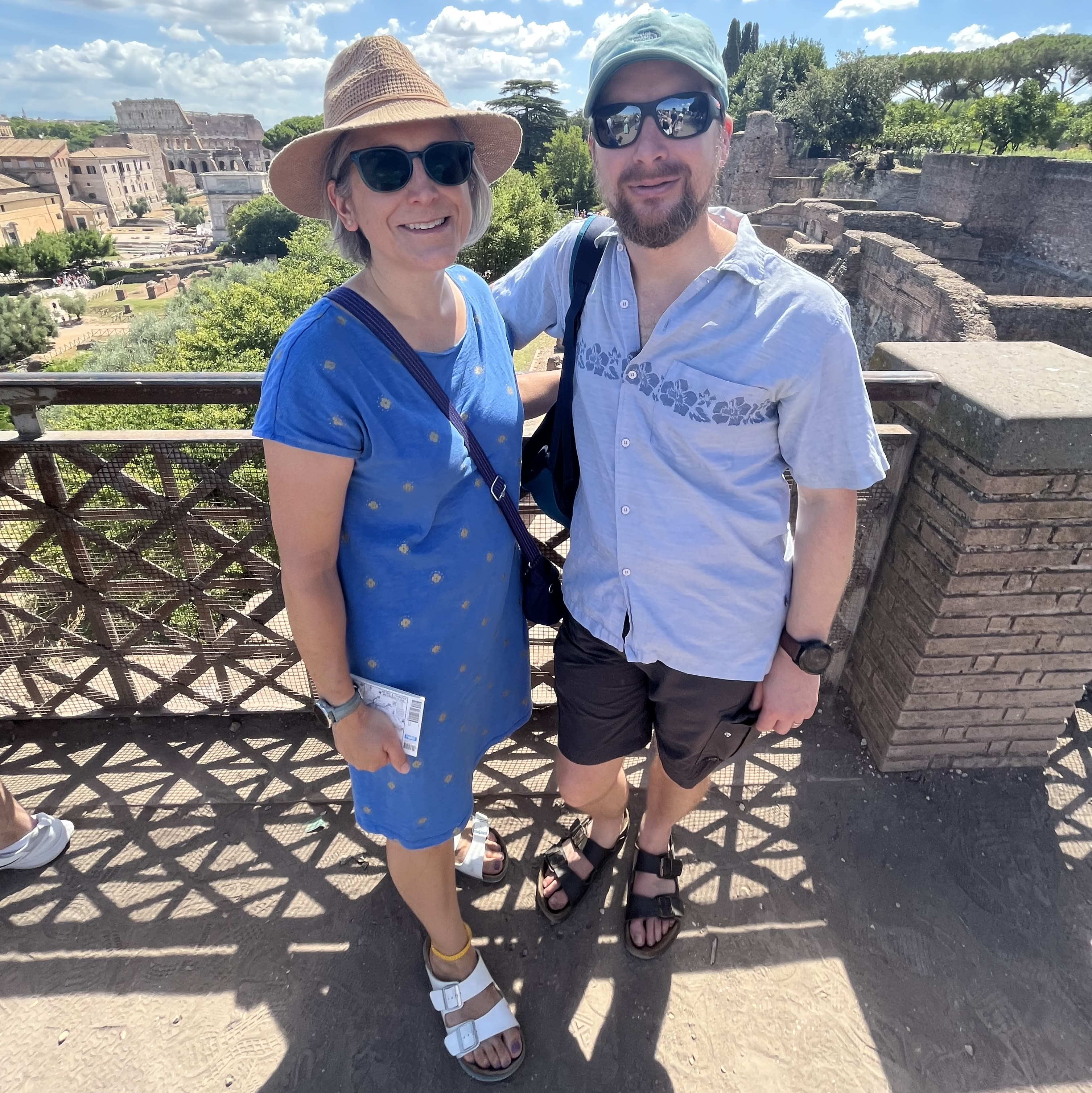 A couple wearing sunglasses and hats posing for a photo in the sun