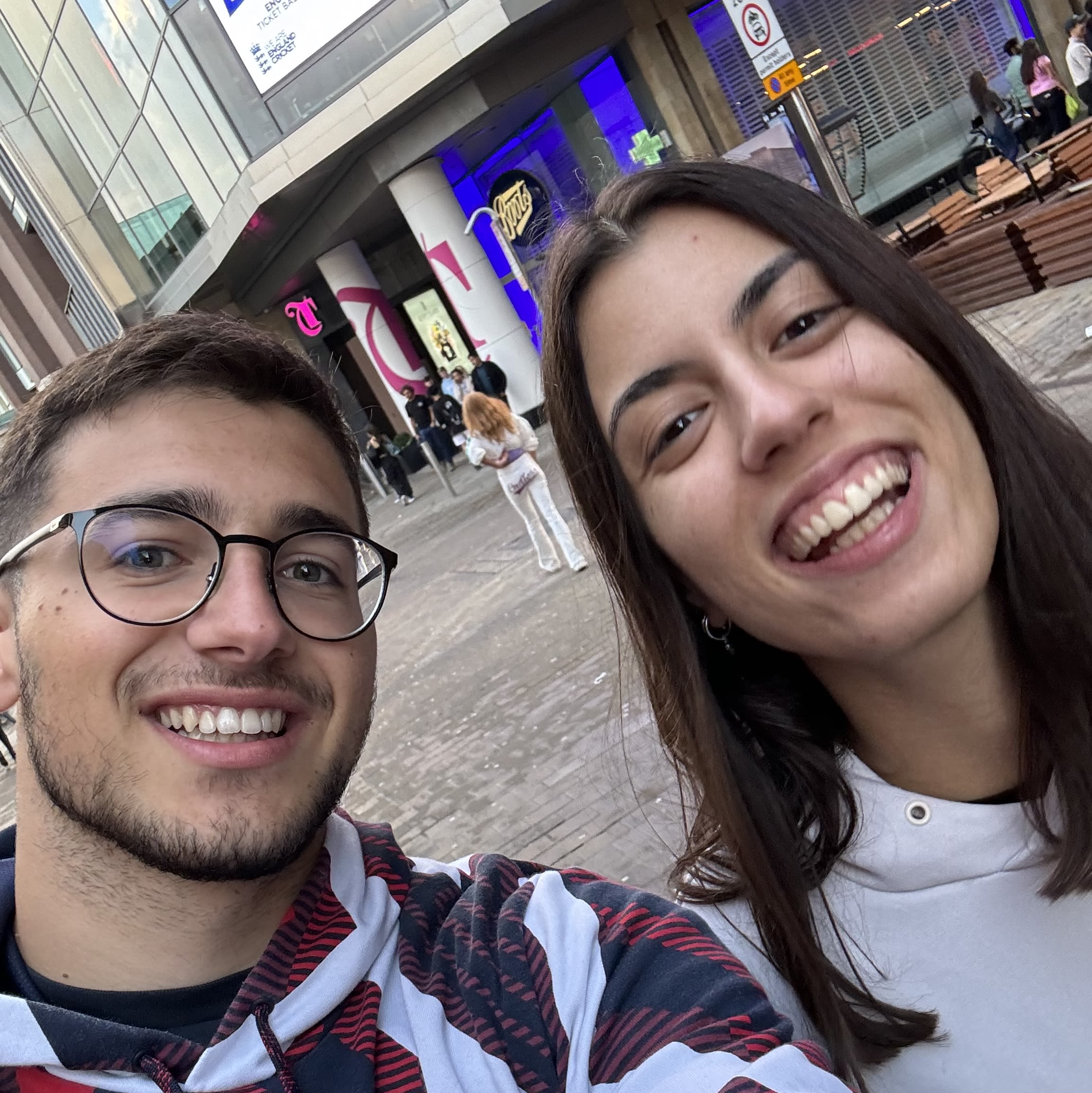 A man and a woman smile for a selfie in the street