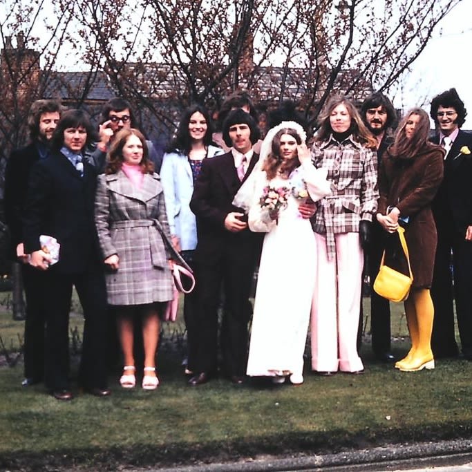 A wedding photo from the 1970s. A group of smartly dressed people pose for a photo