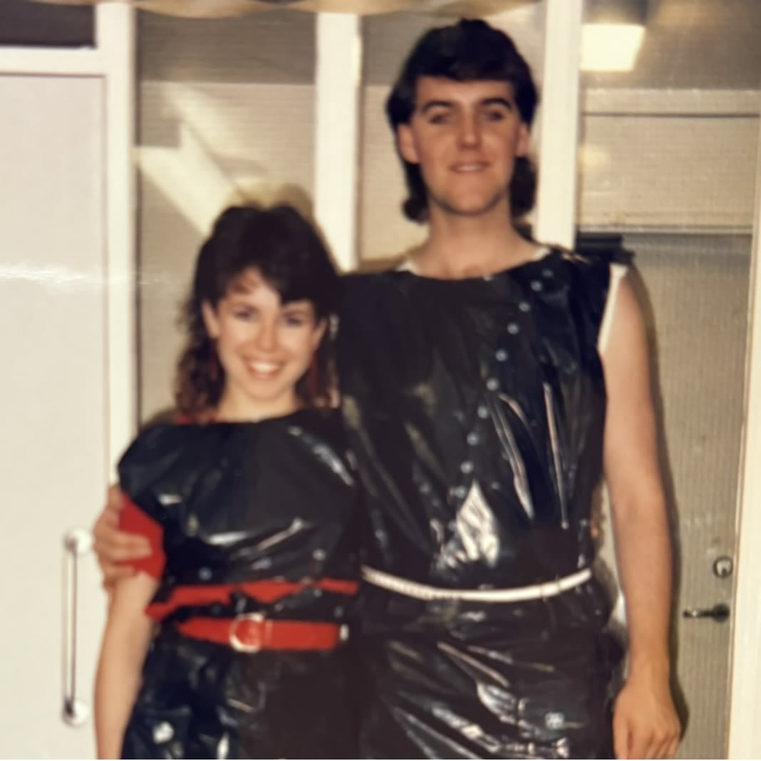 A photo of a man and woman in the 1980s wearing fancy dress and posing for a photo