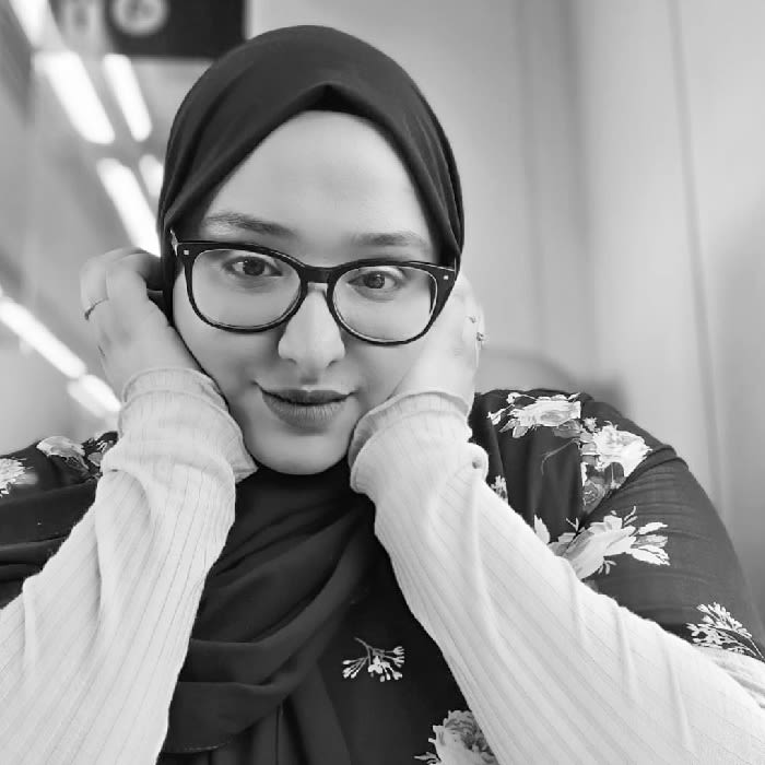 Black and white photo of Asma Amjad with her head resting on her hands