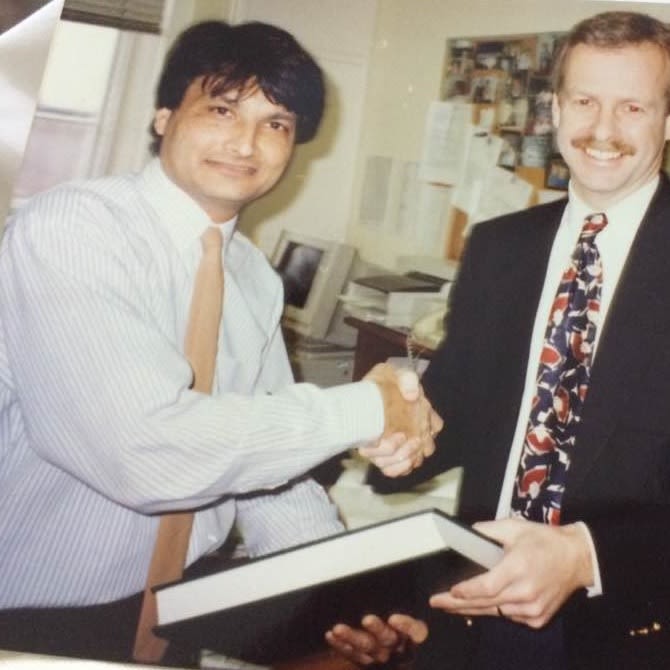 Photo of Hafeez Ul Rahman Memon shaking hands with another man and holding a book