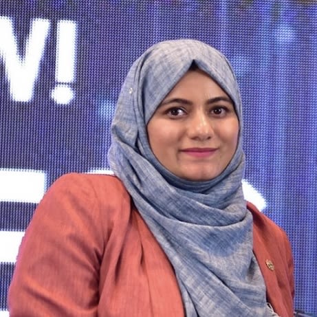 Image of Nousheen Zakaria stood in front of a large screen