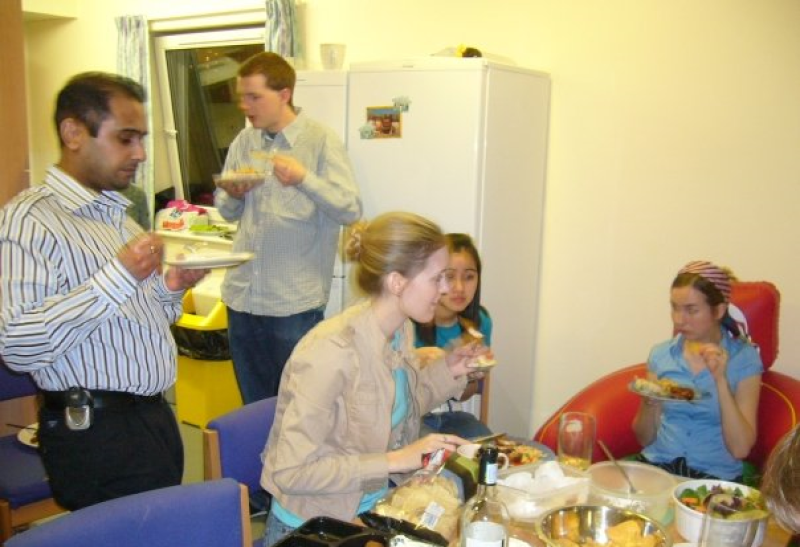 Friends sit and stand in a student kitchen enjoying food