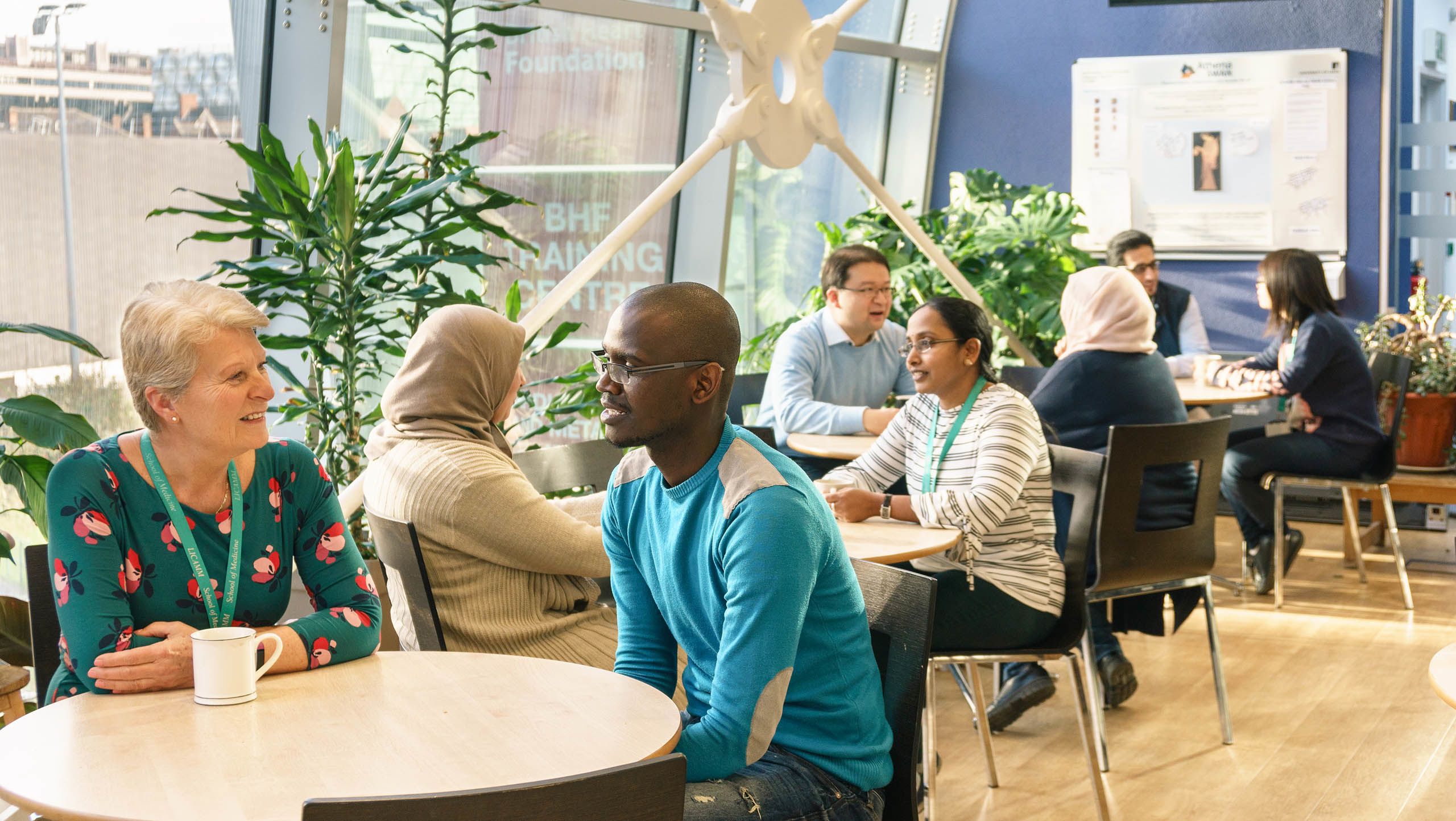 Students and staff sittingaround tables in a cafe