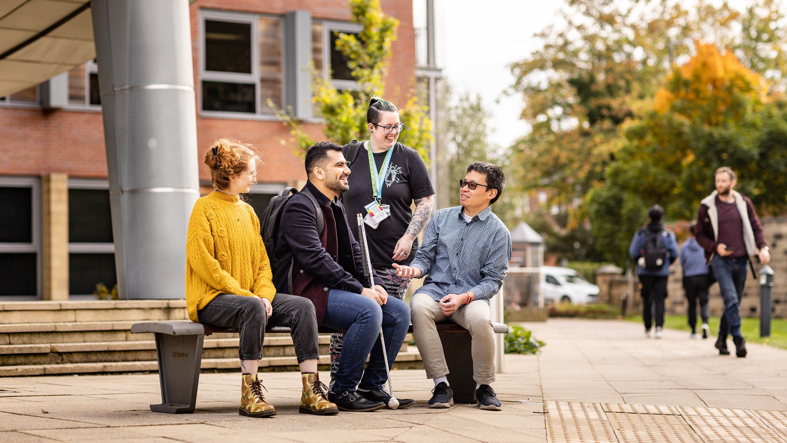 Staff and students chatting on a bench on campus