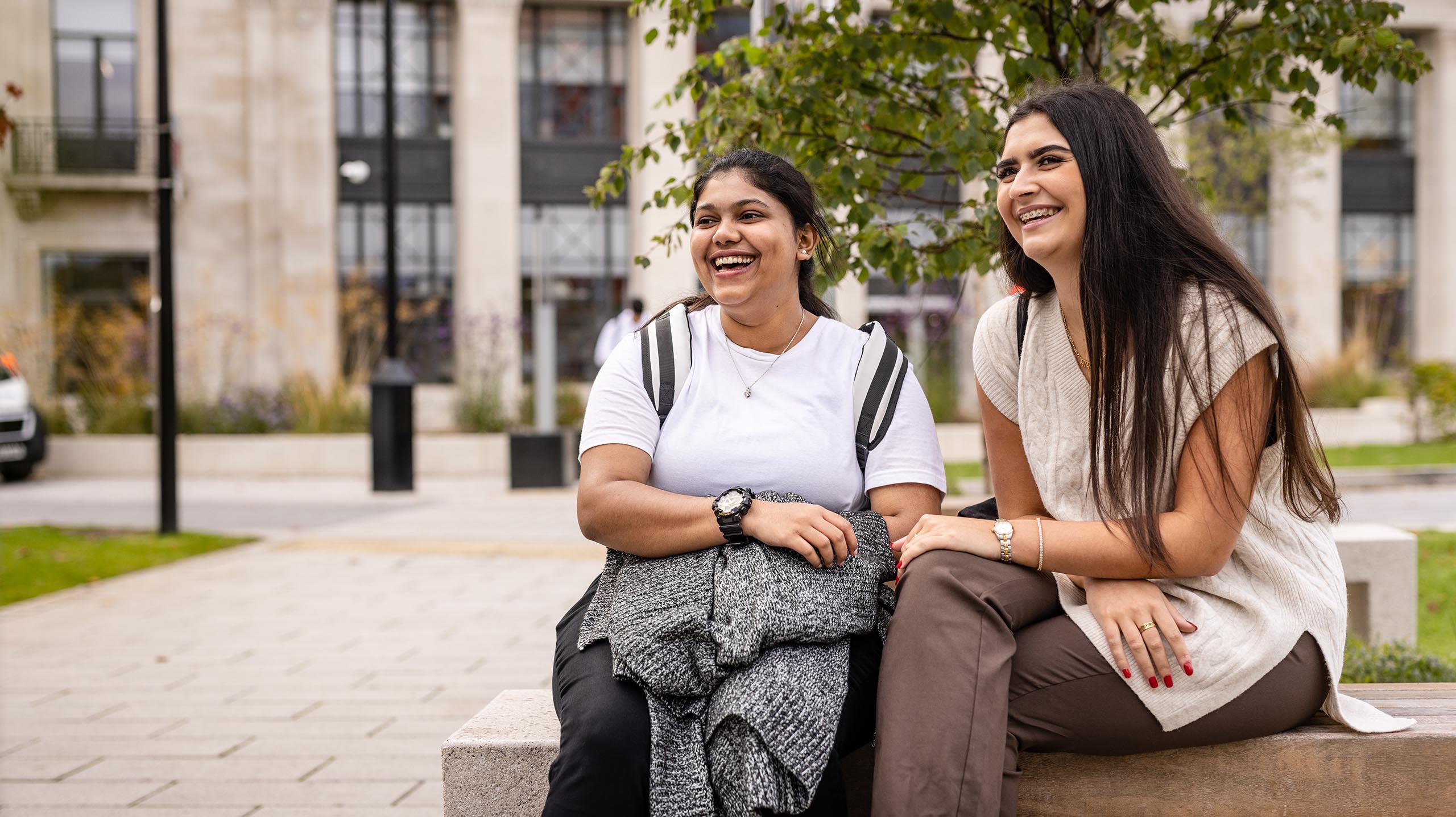 Two students sitting on a bench outside the Bragg building