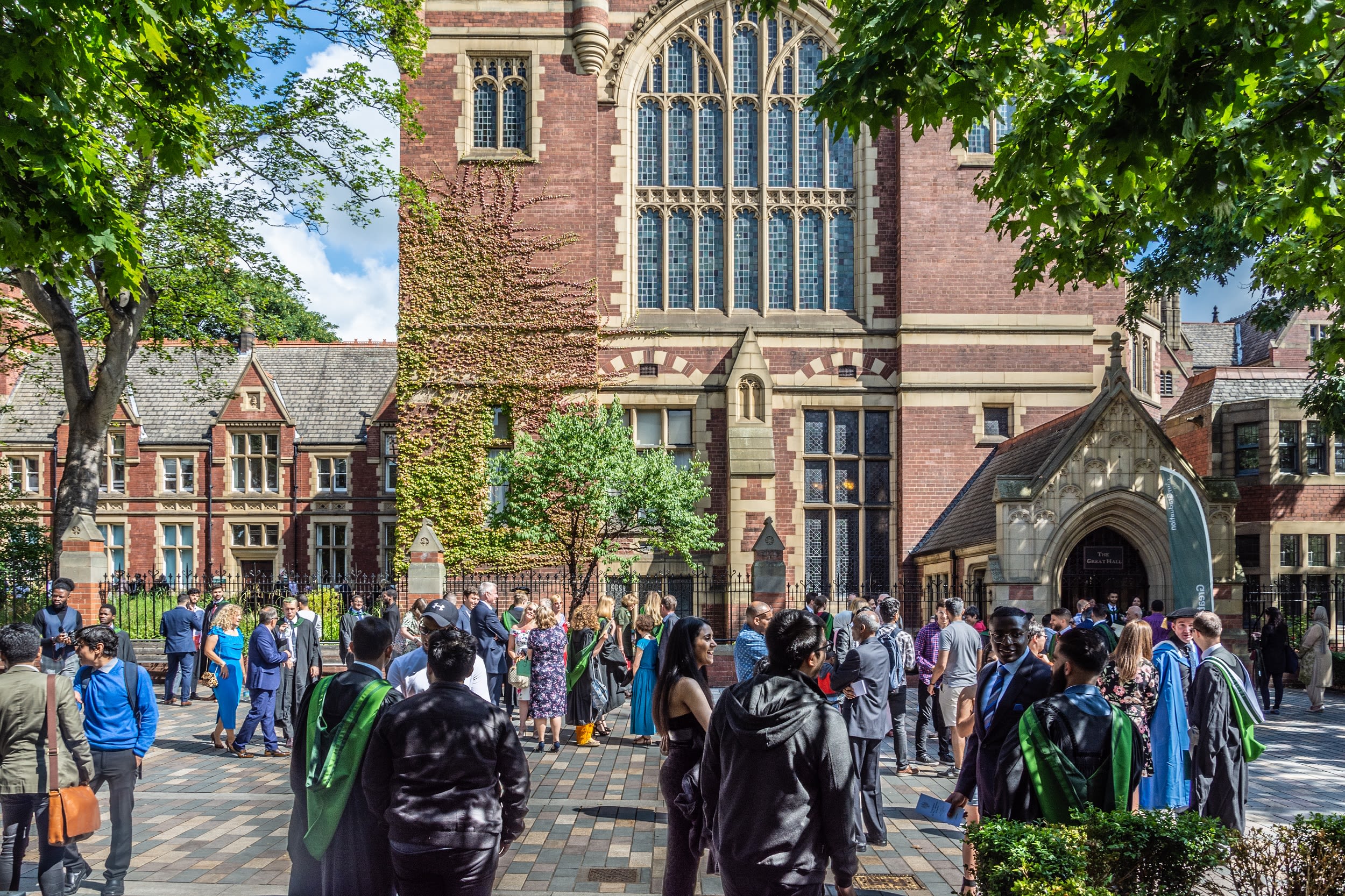 Lots of students in gowns and their guests outside the Great Hall at a graduation ceremony.