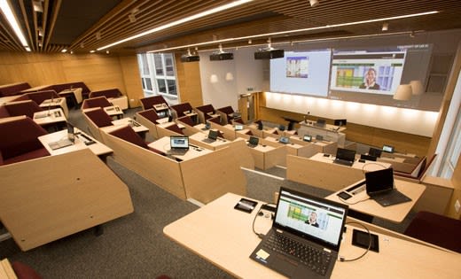 A lecture theatre at the University of Leeds with laptops on desks and a screen at the front.