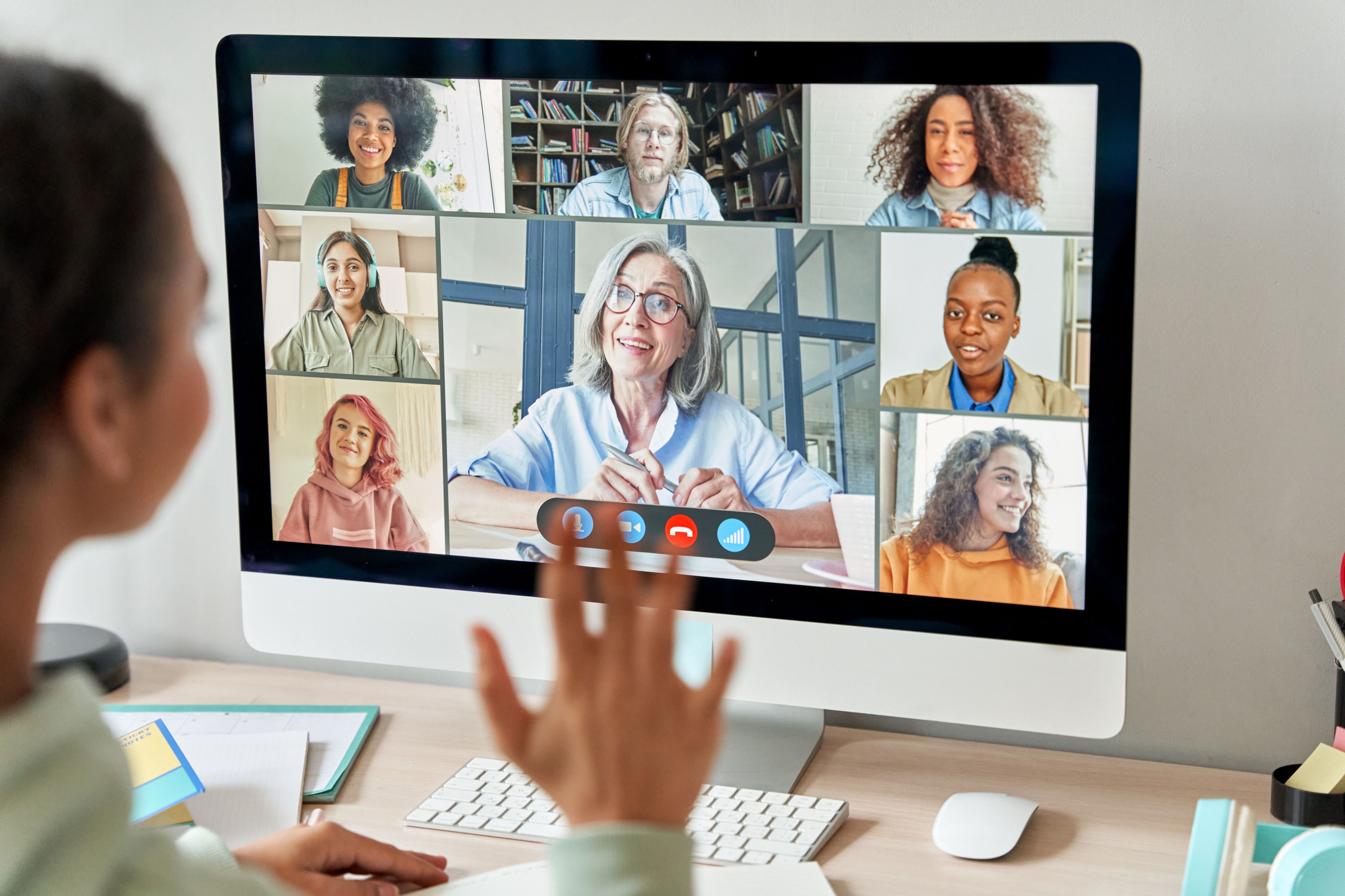 A female student conducting a video conference call with several participants, using a desktop computer.