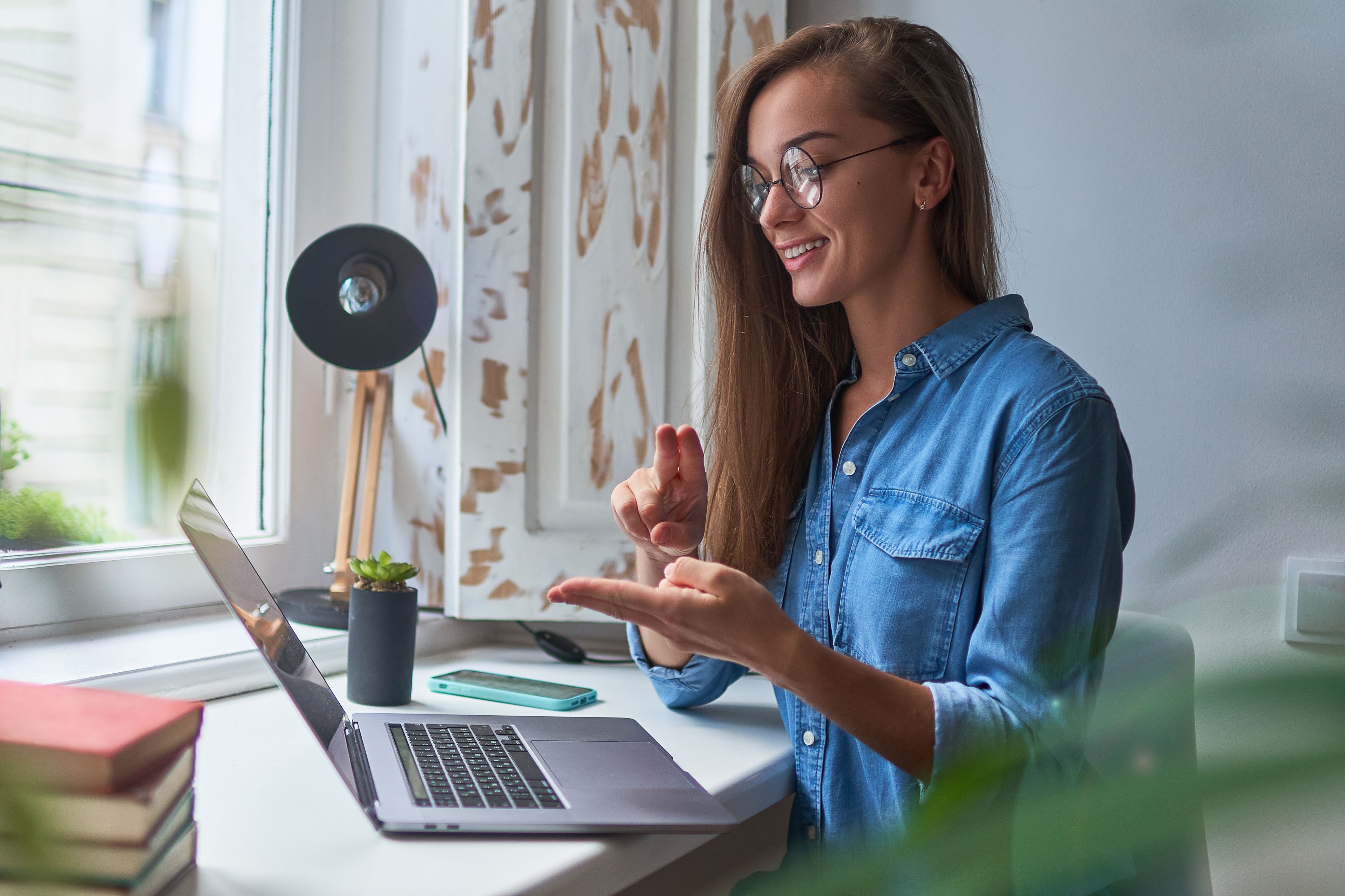 A woman using a laptop with video conferencing software combined with sign language.