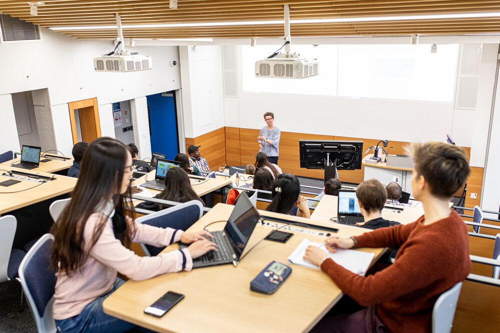Students in a lecture theatre using laptops and mobile devices combined with face-to-face teaching.