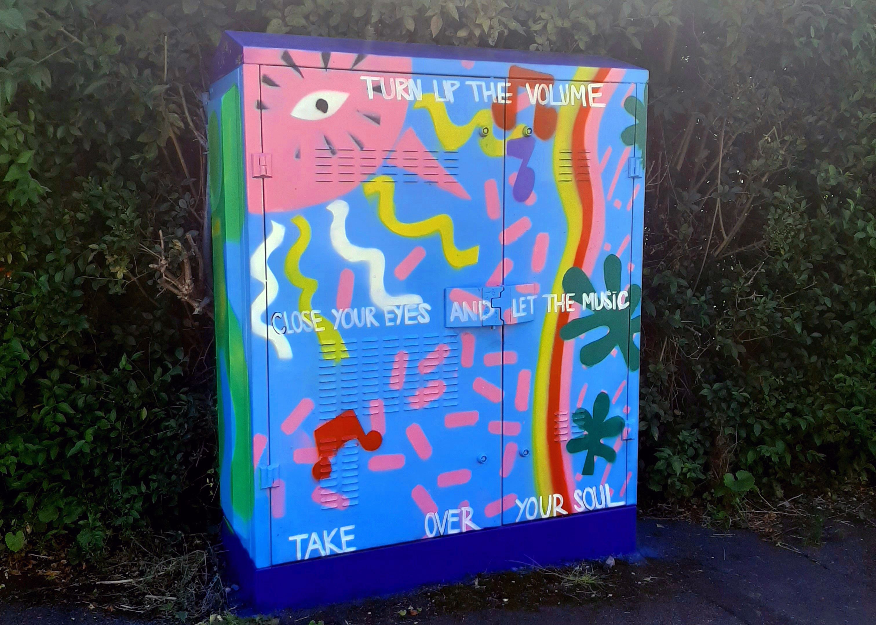 Street artwork depicting sunlight and music, with the text: Turn up the volume, close your eyes and let the music take over your soul. Turn Up The Volume by Ria. Image courtesy Pyramid Arts.